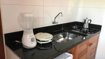 Cozinha com liquidificador, cafeteira e pia.