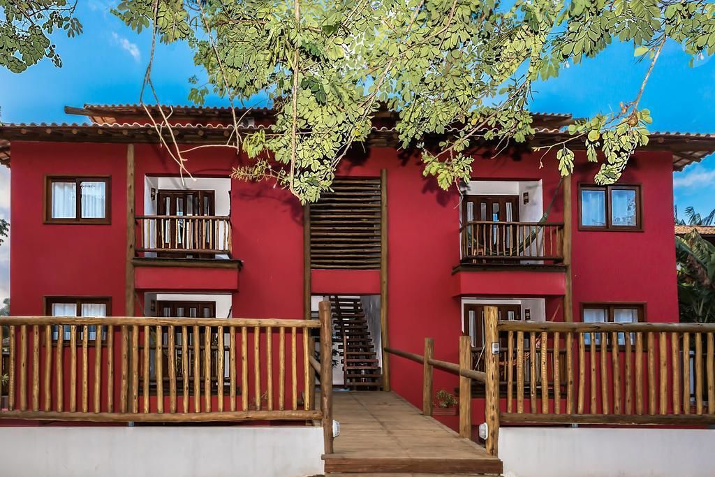 Um edifício vermelho com várias varandas e uma escadaria de madeira que leva à entrada.