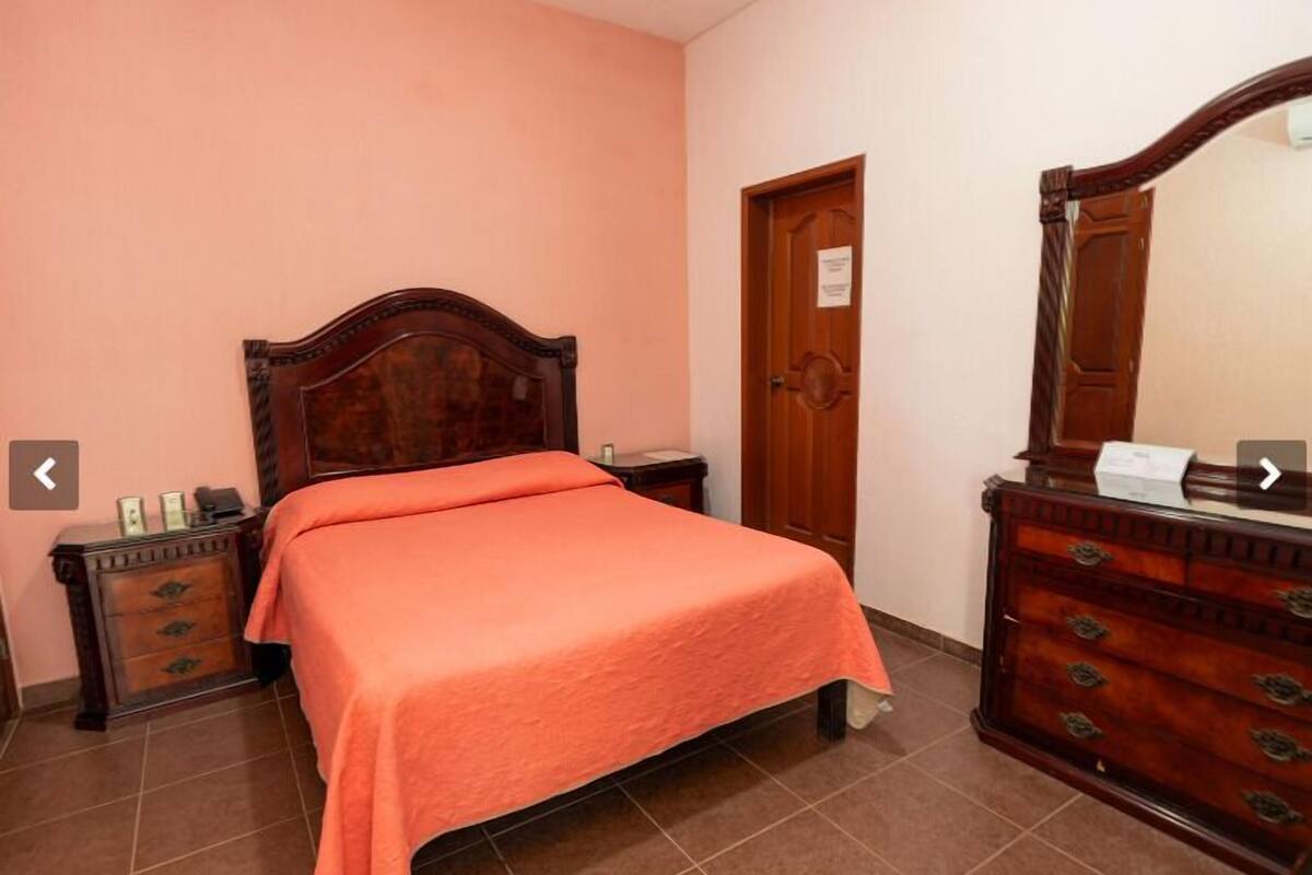 Un dormitorio con una cama de madera, un aparador y una puerta.