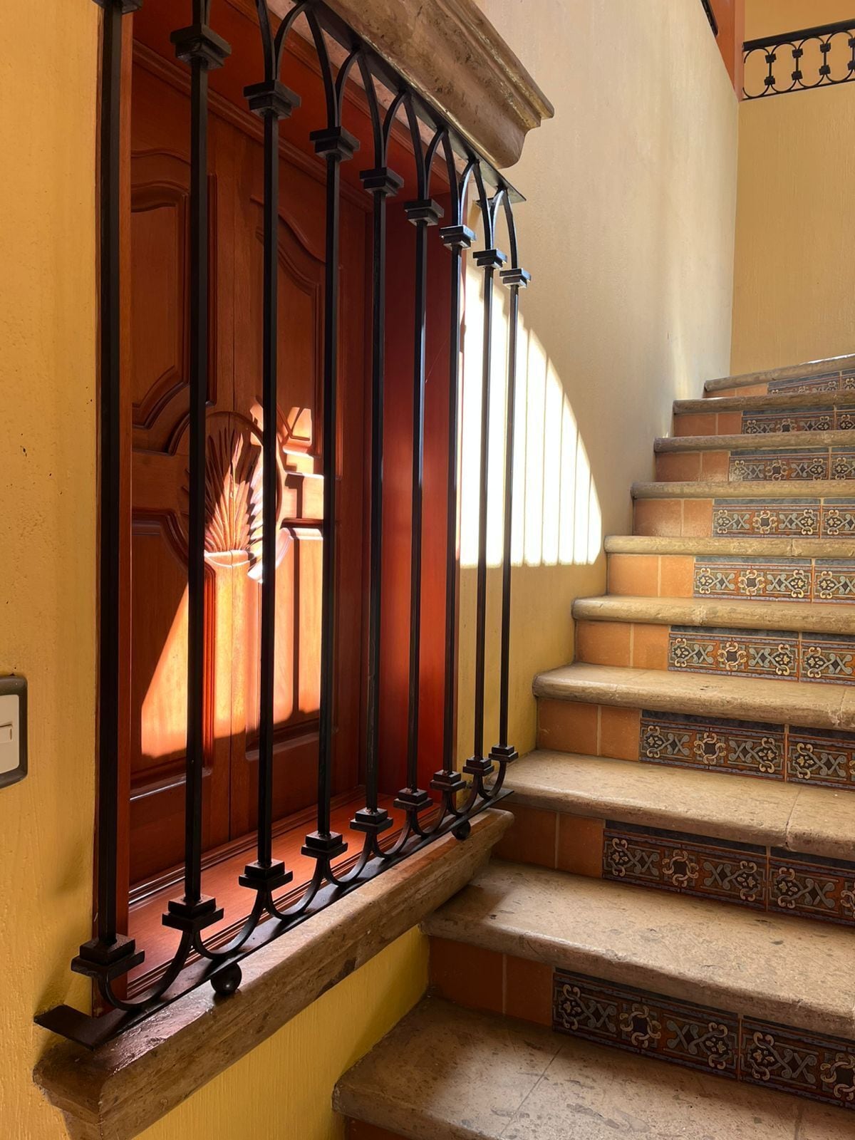 A staircase with ornate metal railings and patterned tile steps.