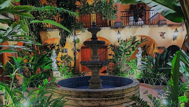 A courtyard with a central fountain, surrounded by lush greenery and a tiled floor. - Hotel Casa La Gran Senora (Tequila)