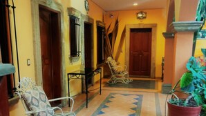 A hallway with patterned tiles, a potted plant, and two chairs. - Hotel Casa La Gran Senora (Tequila)