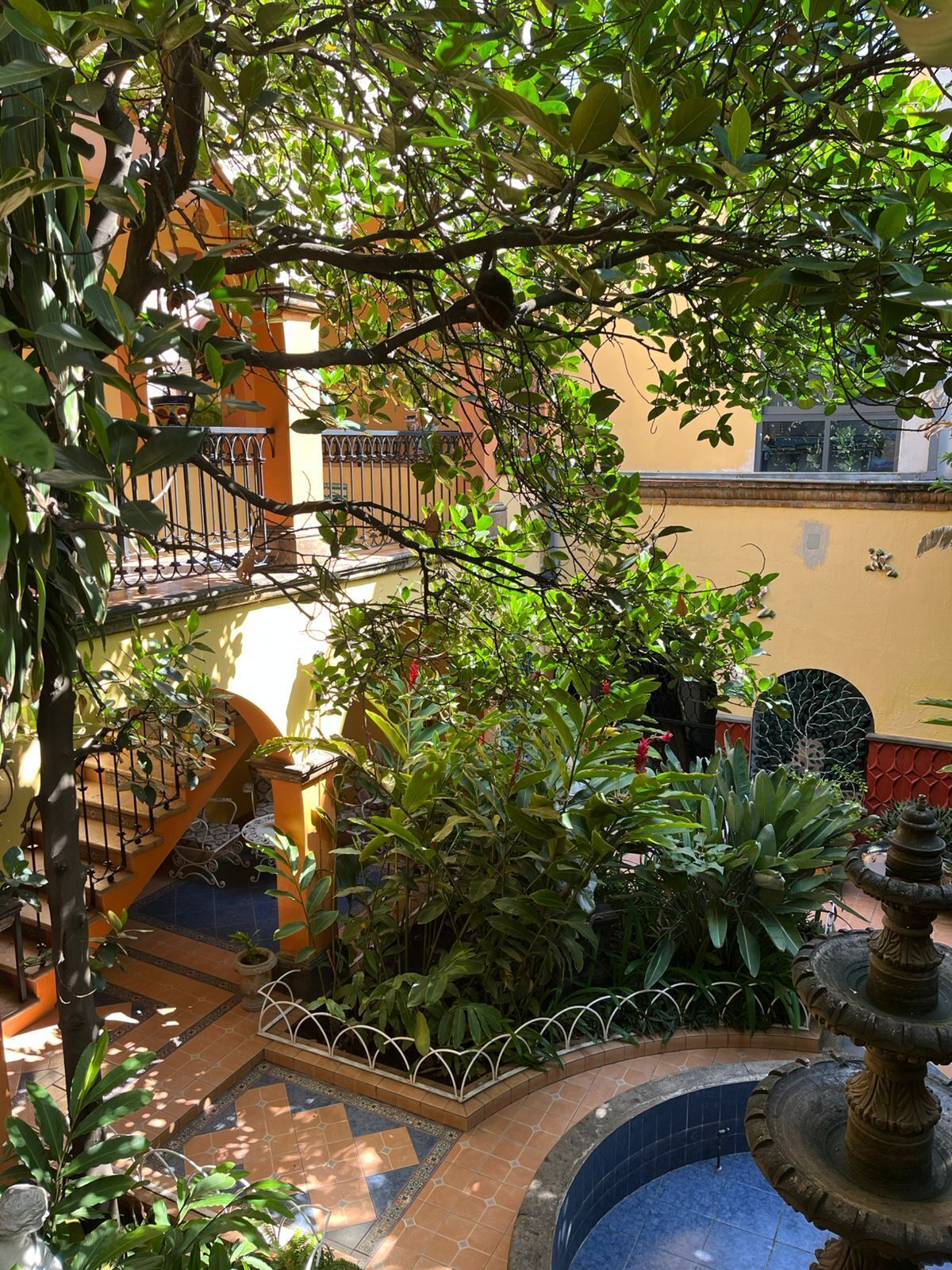 A courtyard with a fountain, a staircase, and a railing.