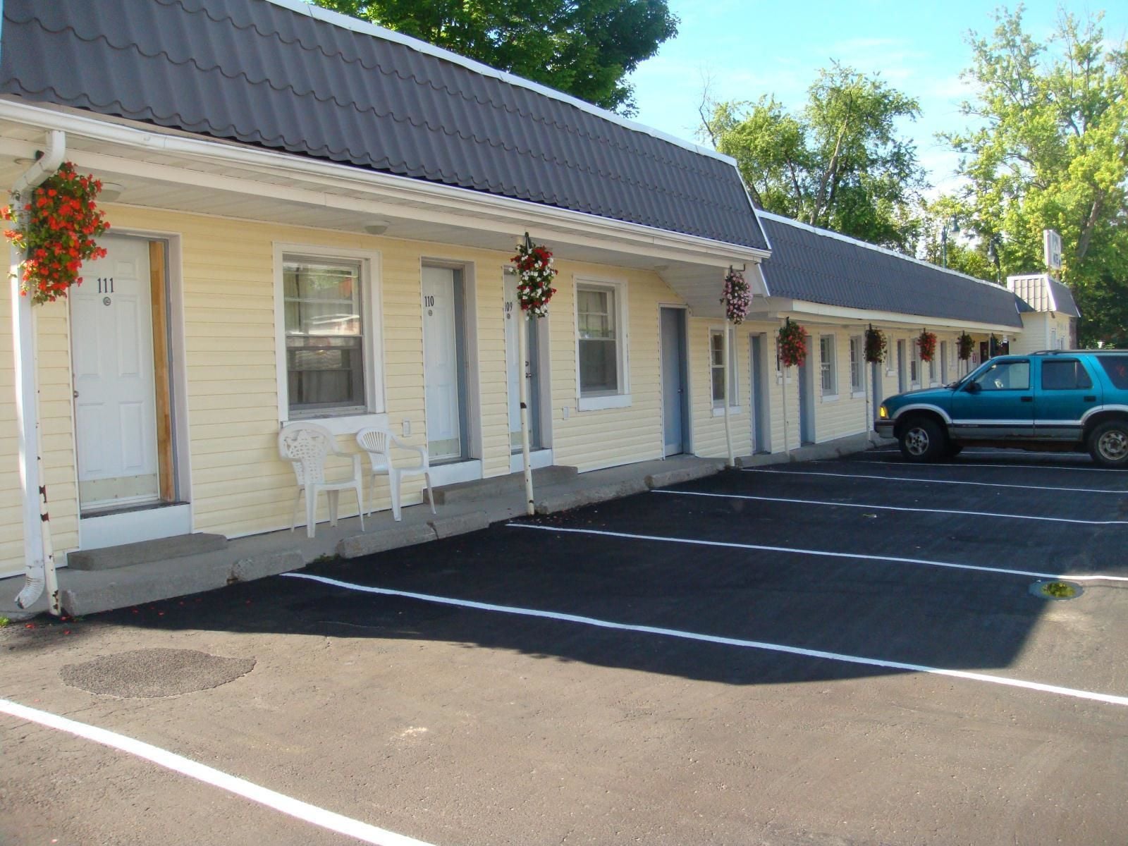 Un motel con habitaciones numeradas, un estacionamiento y un automóvil estacionado.