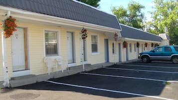 Un motel con habitaciones numeradas, un estacionamiento y un automóvil estacionado.