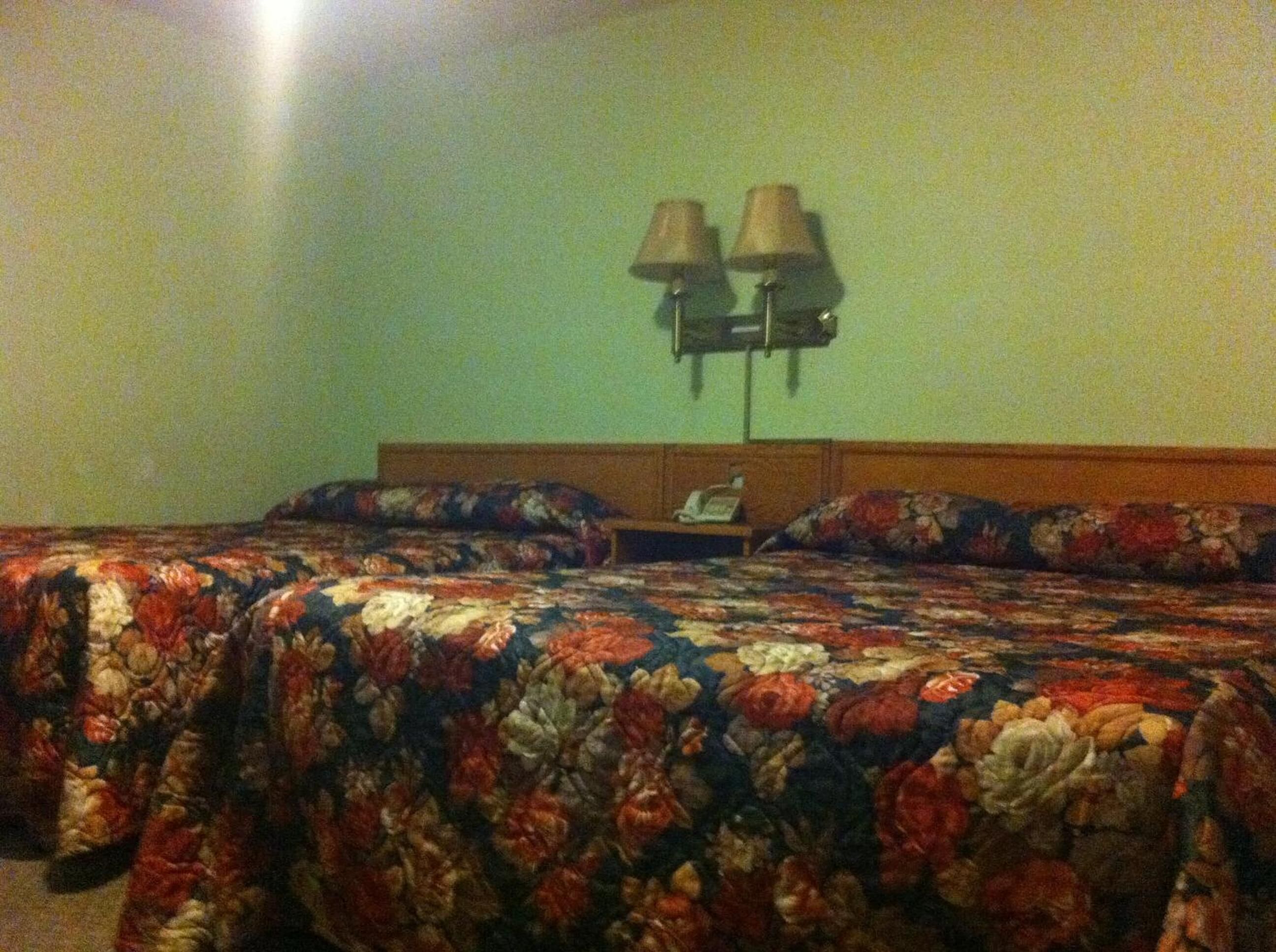 Une chambre d’hôtel avec un grand lit, une table de chevet et deux lampes fixées au mur.