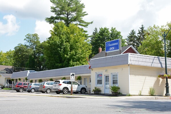 A motel with a signboard, parked cars, and a flag.