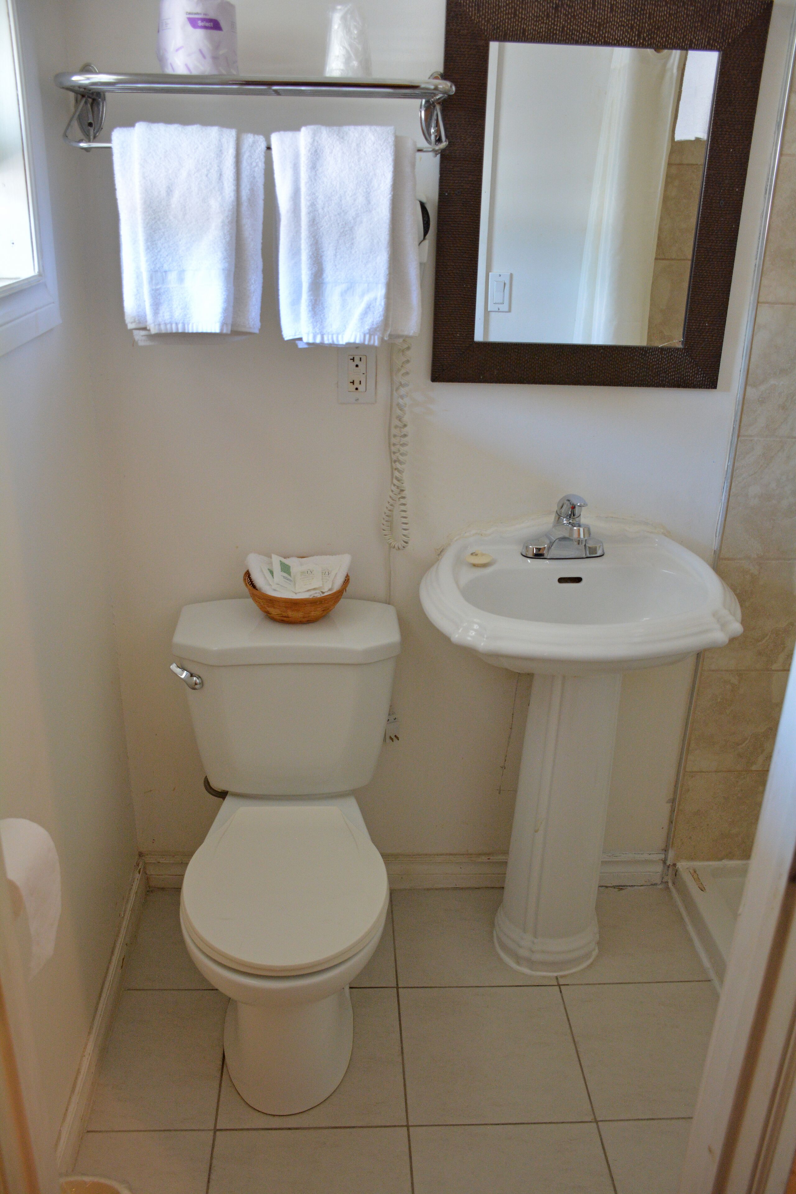 Un baño pequeño con inodoro, lavamanos, espejo y toallero.