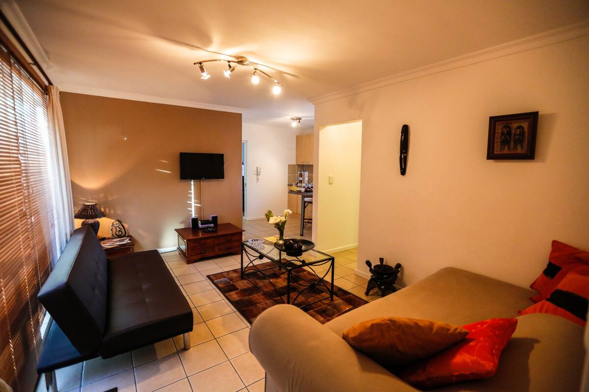 Una sala de estar con un sofá, una mesa de centro y un televisor montado en la pared.