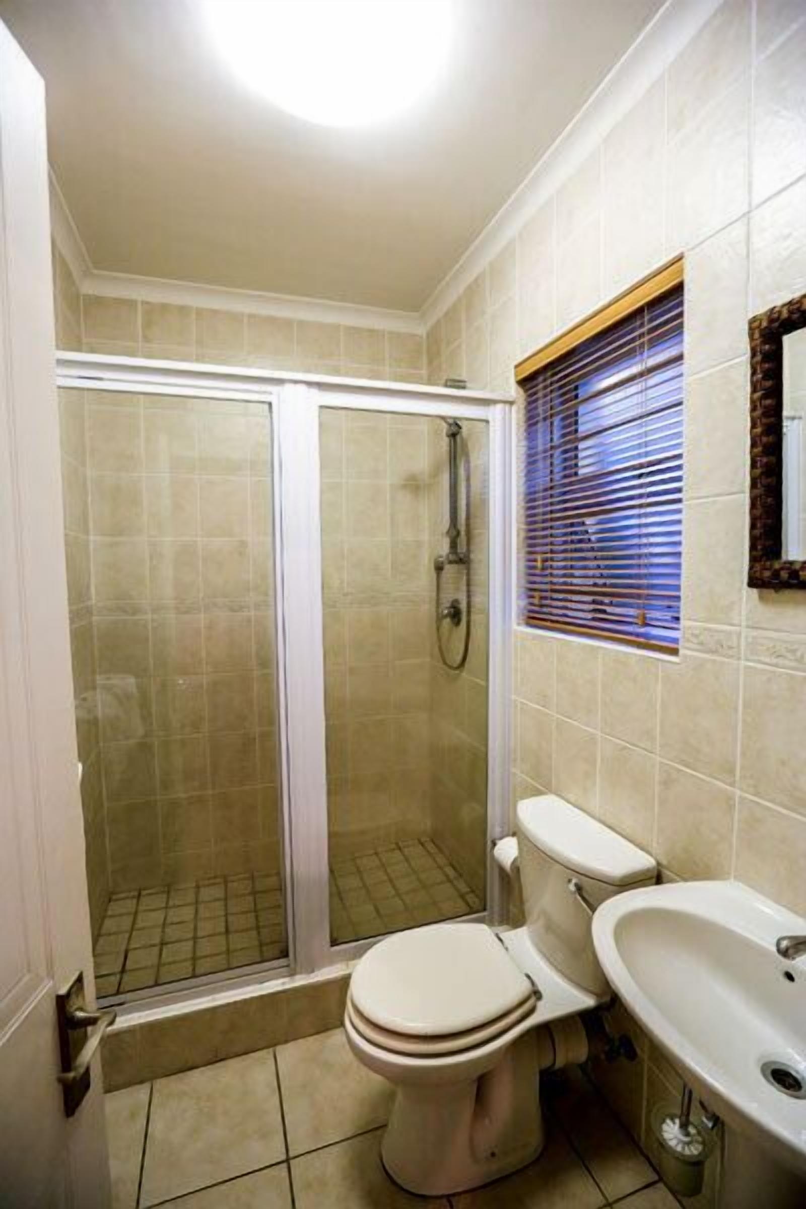 A bathroom with a shower, toilet, and sink.