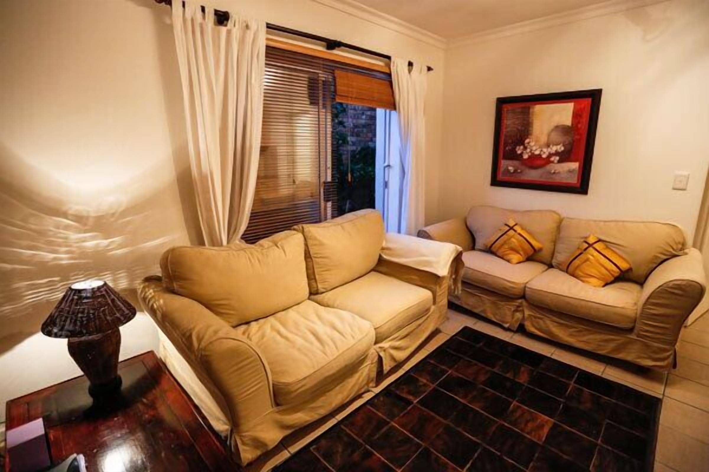 A living room with two beige sofas, a dark wooden coffee table, and a lamp.