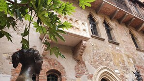 A historic building with a statue in front, brick walls, and arched windows. - Hotel Aurora (Verona)