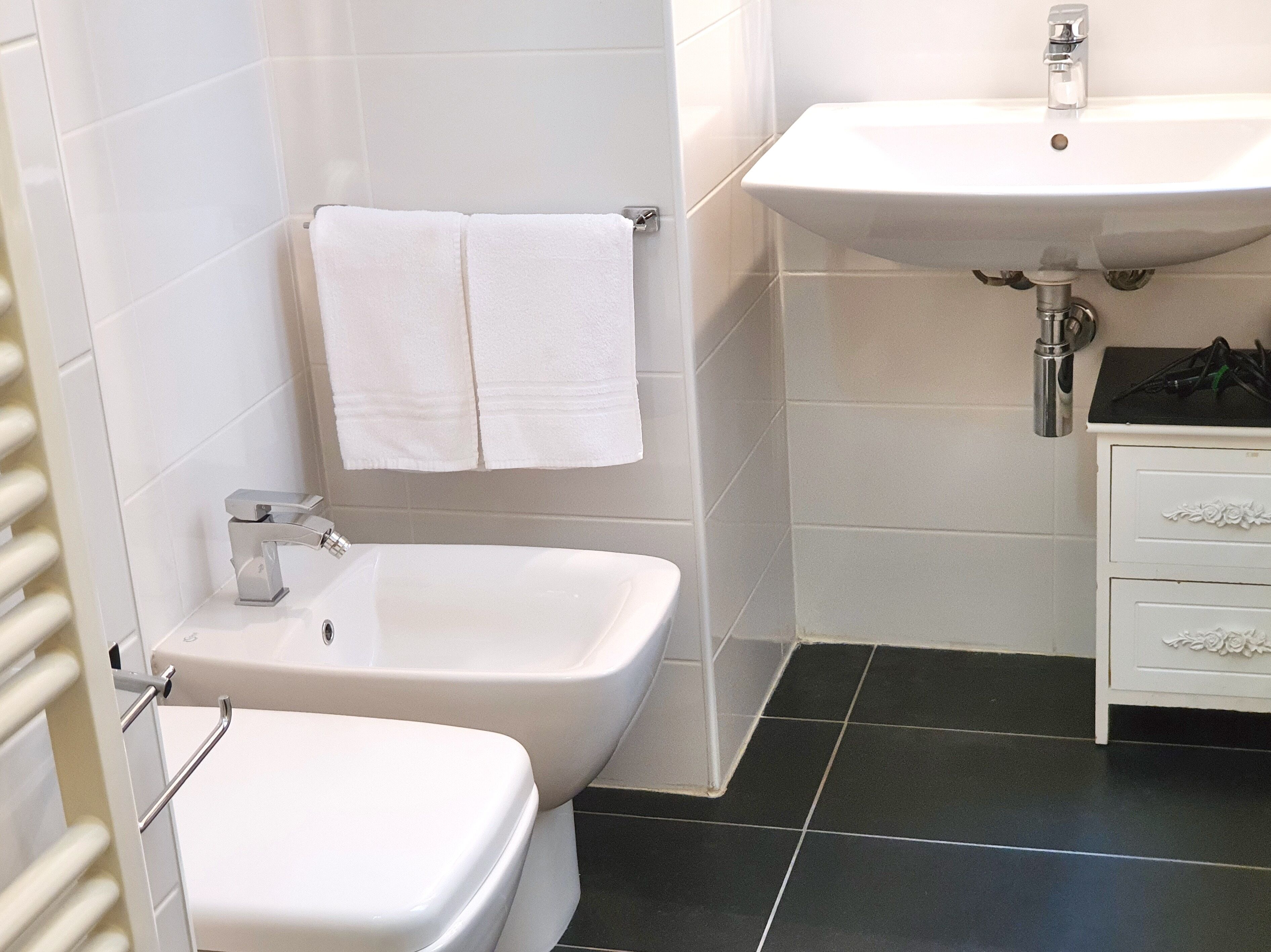 Un baño con una bañera blanca, un inodoro blanco, un lavabo blanco y un perchero para toallas.