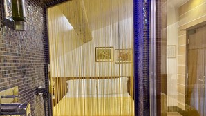 A luxurious bathroom with a large mirror, a gold-colored shower enclosure, and a tiled wall. - Hotel Aurora (Verona)