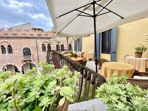 A terrace with outdoor seating, a wrought iron railing, and potted plants. - Hotel Aurora (Verona)