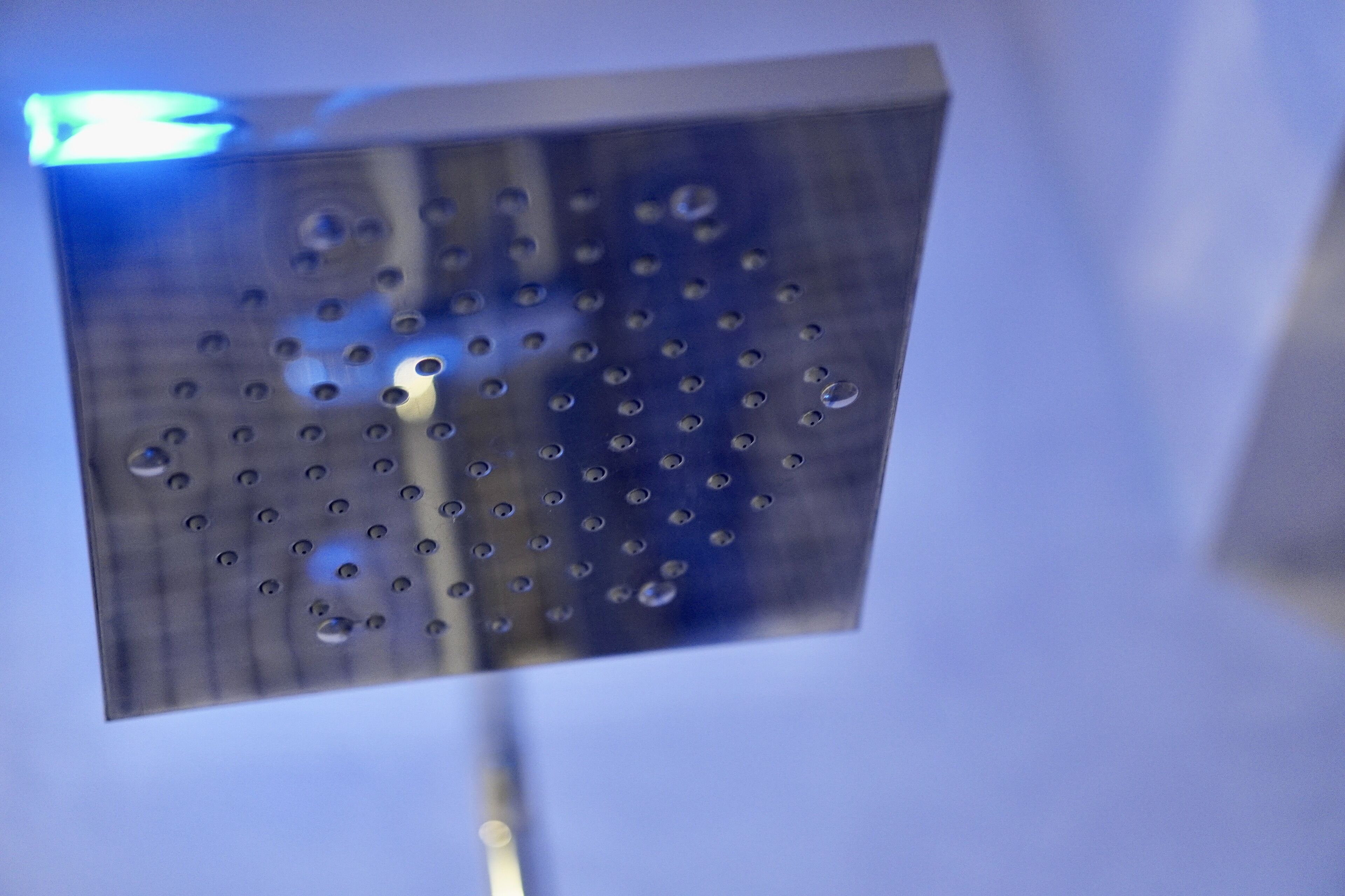 A close-up of a showerhead with water droplets.