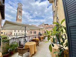 Una terraza con asientos al aire libre, un campanario al fondo y cielo despejado.