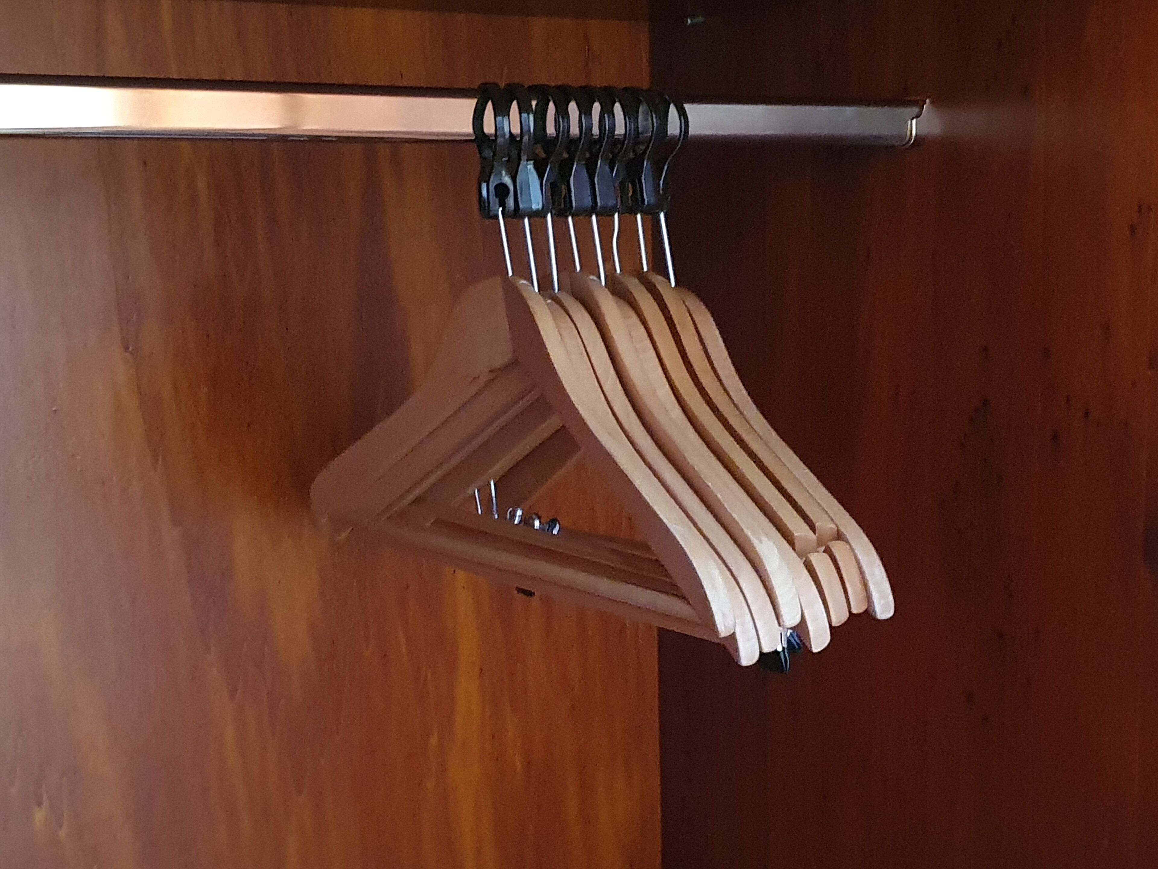A wooden hanger rack with multiple hangers.