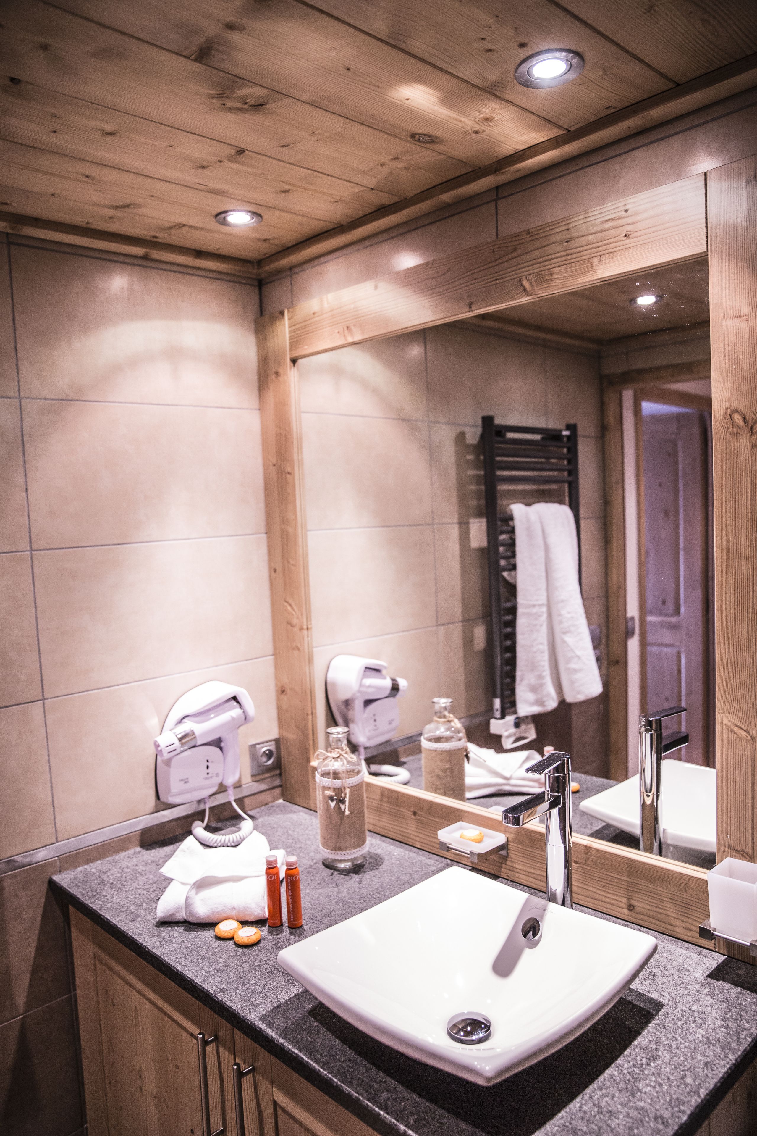 Une salle de bain moderne avec un grand miroir, un lavabo blanc et un porte-serviettes.