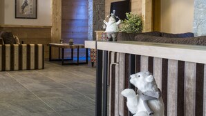 A modern interior with a wooden ceiling, stone wall, and a bar area with a polar bear sculpture. - CGH Résidences Boutique Le Napoléon (Montgenevre)