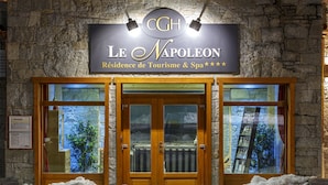 A hotel entrance with a stone facade, double wooden doors, and a sign above reading "Le Napoleon Residence de Tourism & Spa". - CGH Résidences Boutique Le Napoléon (Montgenevre)