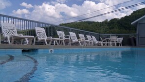 Une piscine entourée de chaises longues blanches et d’une clôture en métal.