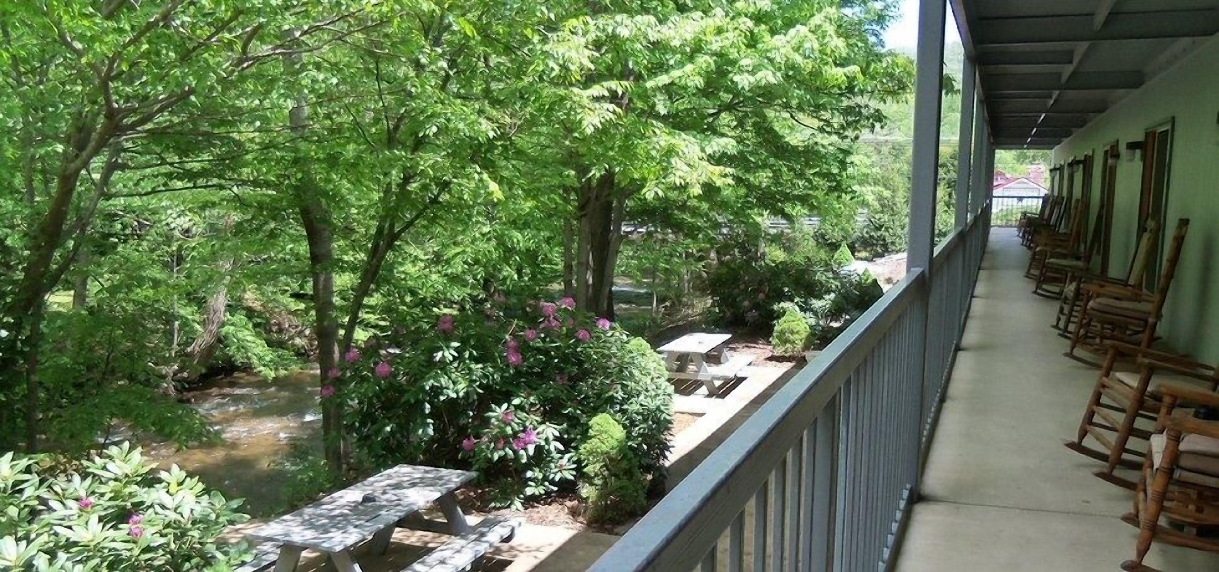 A covered outdoor area with a row of wooden rocking chairs and a small table.