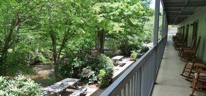 A covered outdoor area with a row of wooden rocking chairs and a small table.