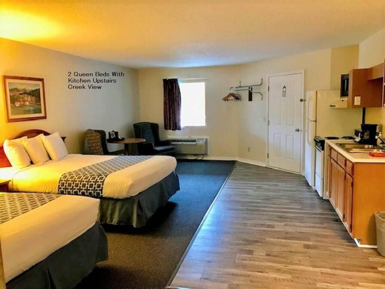 Ein Hotelzimmer mit zwei Queensize-Betten, einer Küchenzeile, Blick auf die Küche und einer Tür nach draußen.