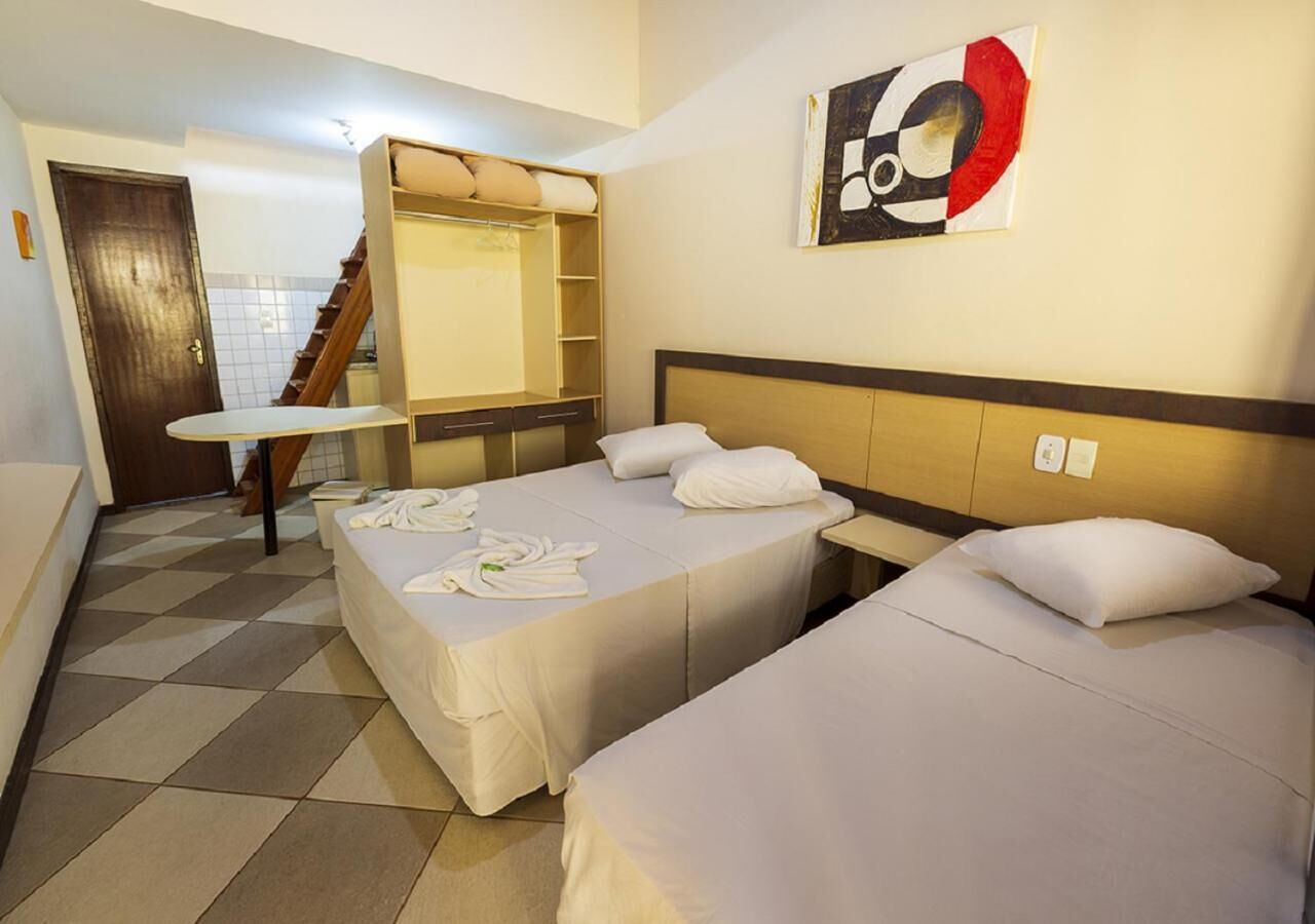 A hotel room with two beds, a desk, a chair, a wardrobe, and a staircase.