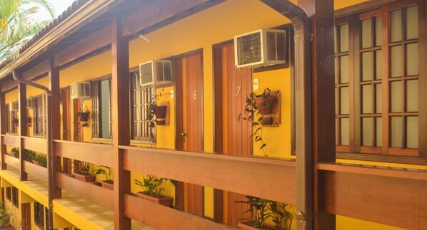 Una hilera de habitaciones con balcones de madera, cada una con una ventana y una puerta.