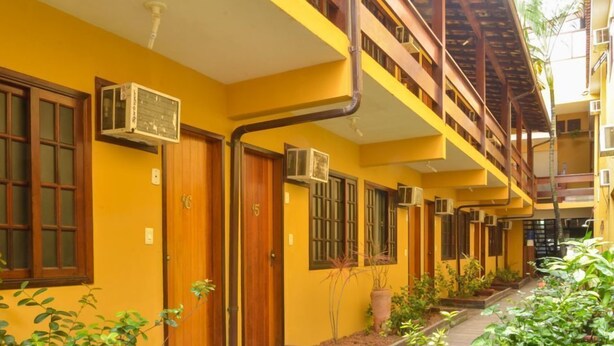 Um edifício amarelo com várias portas e janelas, algumas com aparelhos de ar condicionado.