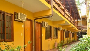 Un edificio amarillo con múltiples puertas y ventanas, algunas con unidades de aire acondicionado.