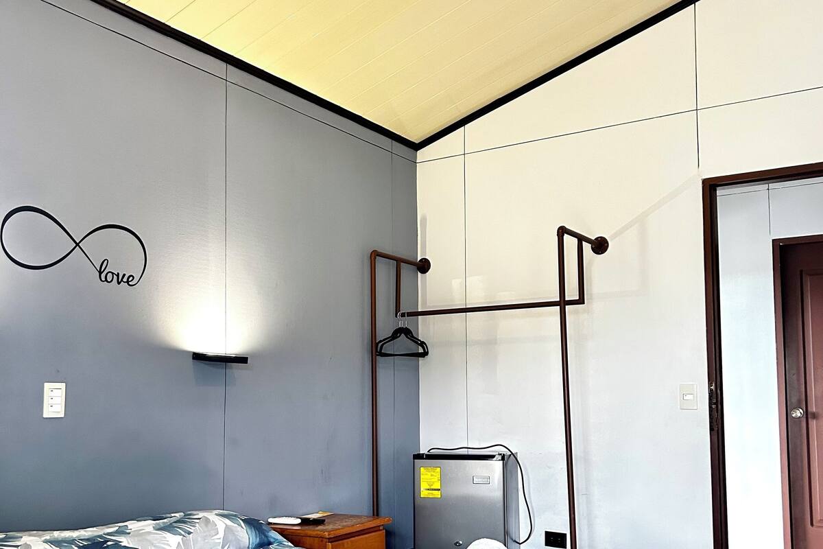 A bedroom with a bed, a wall-mounted light, a heater, and a door.