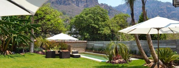 A backyard with a swimming pool, outdoor furniture, and umbrellas.