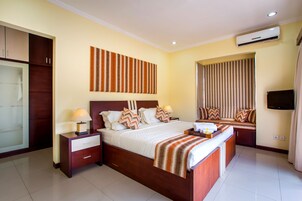 Quarto de hotel com uma cama grande, um guarda-roupa, uma TV e um ar condicionado.