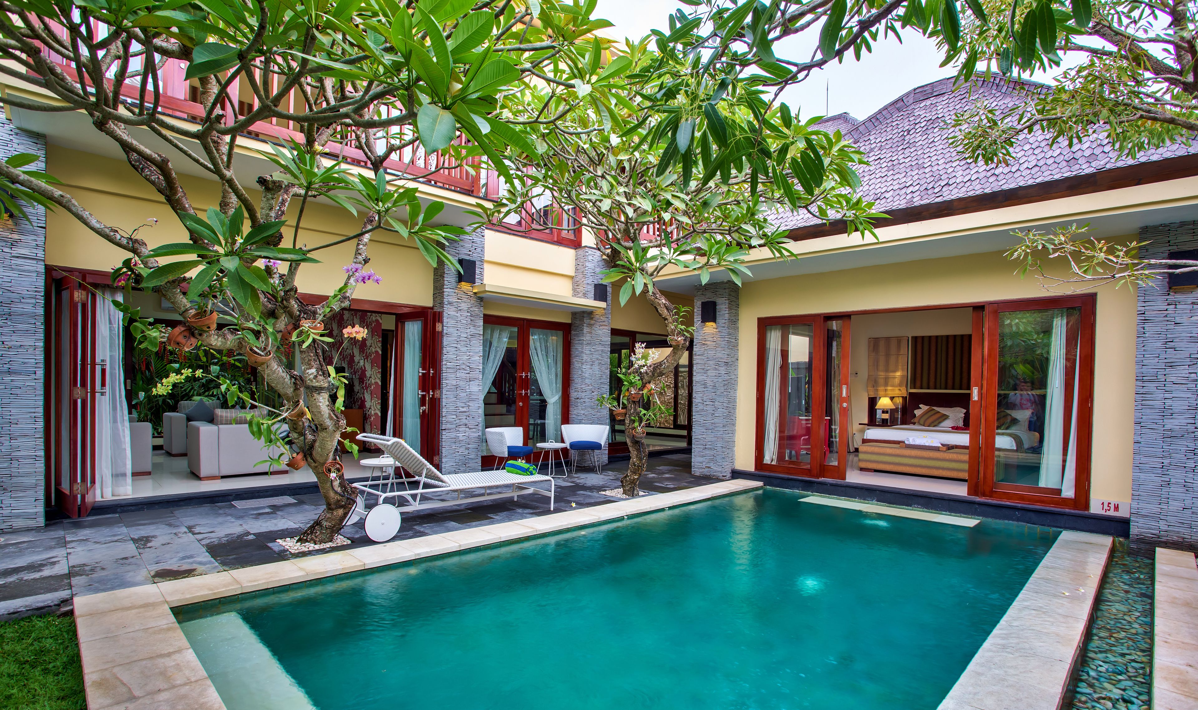 A pool area with a lounge chair, a small table, and a potted plant.