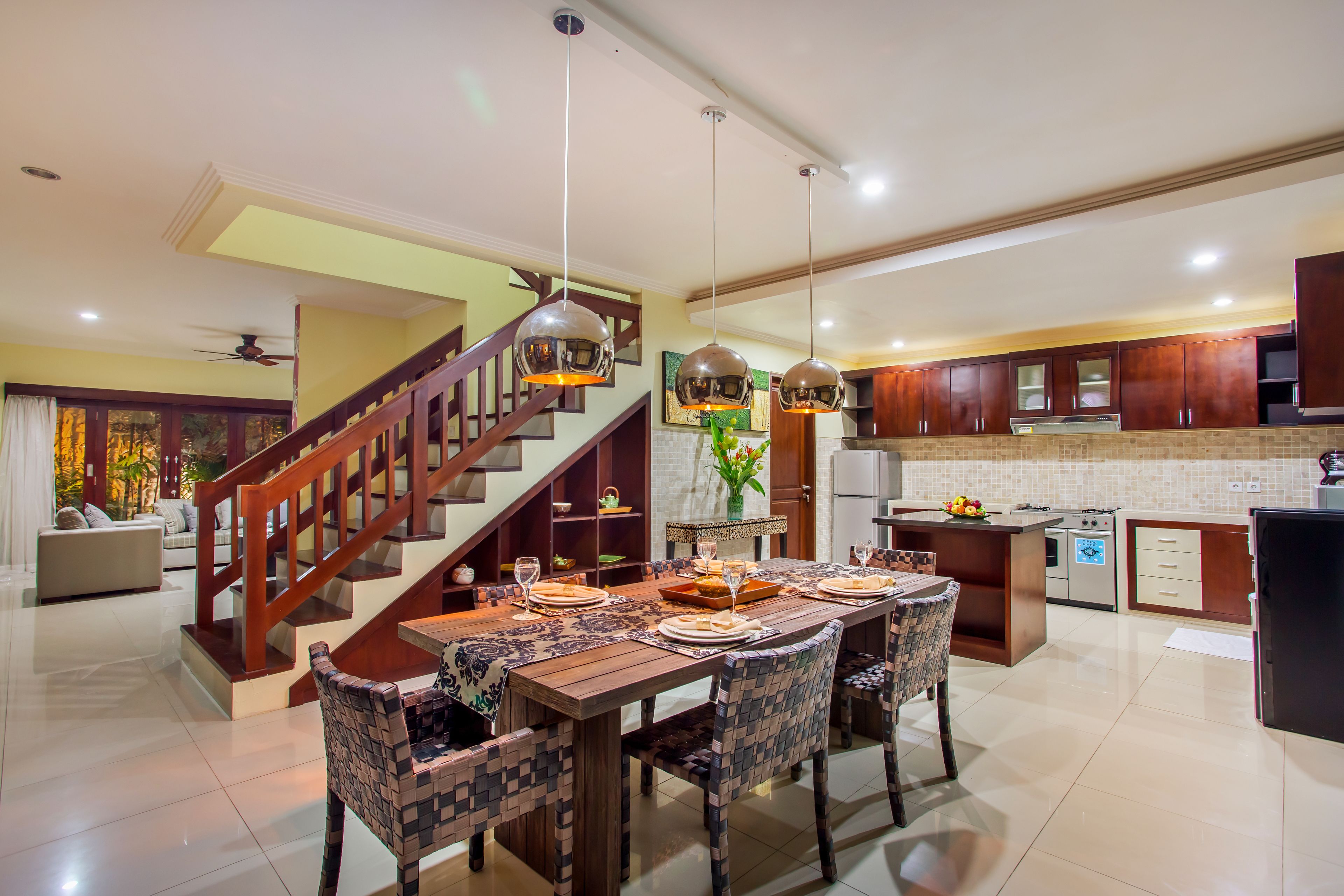 A spacious kitchen with a wooden dining table, modern appliances, and a staircase leading to an upper level.
