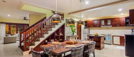 A spacious kitchen with a wooden dining table, modern appliances, and a staircase leading to an upper level.
