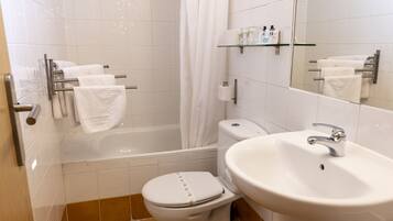 Et badeværelse med badekar, toilet og håndvask.
