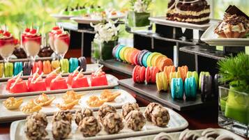 Un buffet proposant une variété de desserts, notamment des macarons aux couleurs vives, des gelées rouges et un gâteau au chocolat.