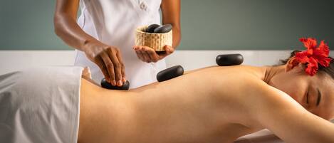 A person receiving a massage with a stone on their back.