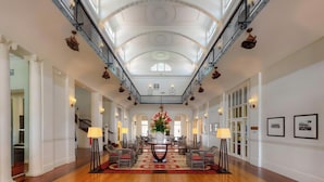 Een ruime lobby met een hoog plafond, sierlijke zuilen en een centraal bloemarrangement.