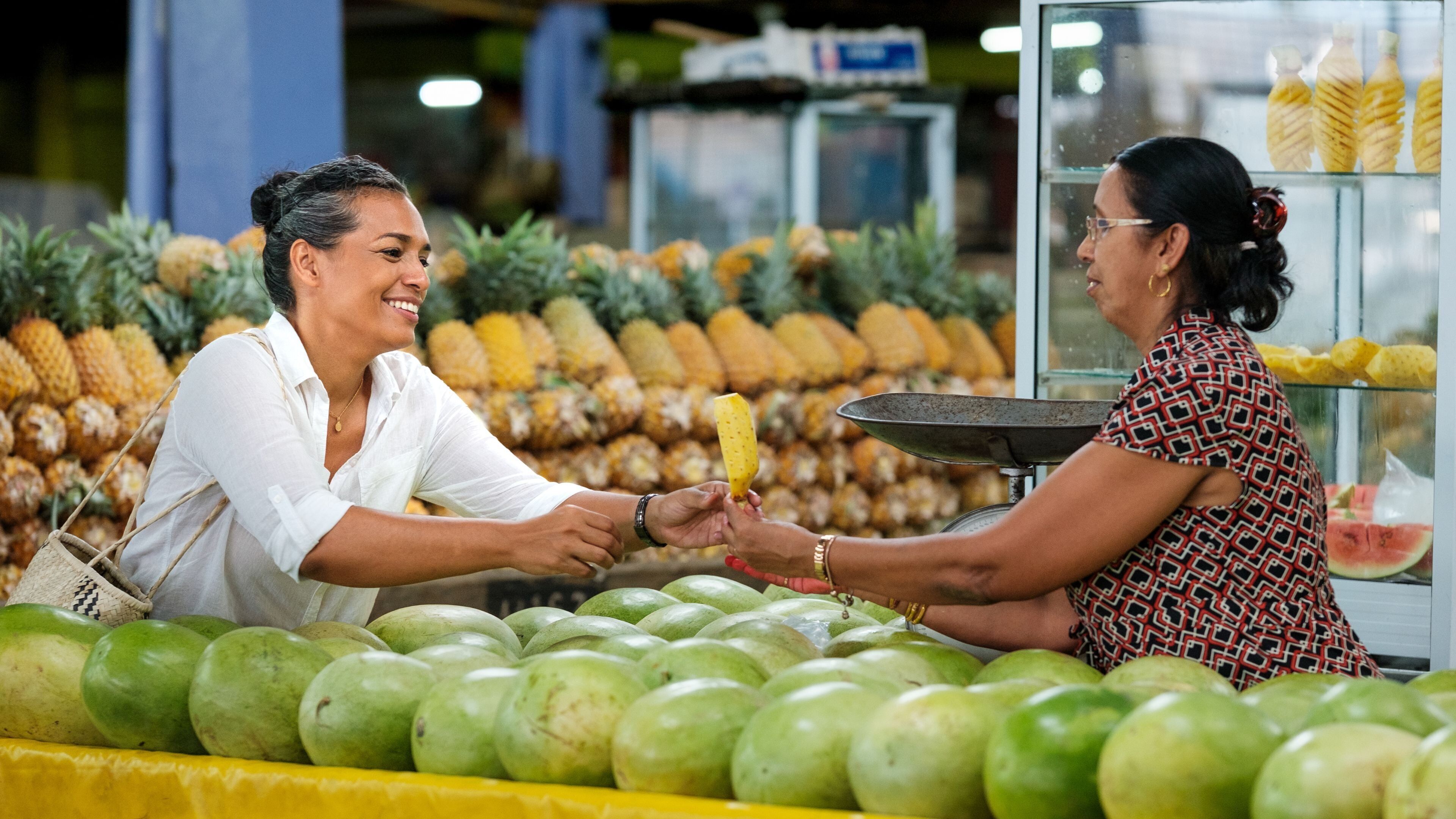 A fruit stand with various tropical fruits like pineapples and watermelons.