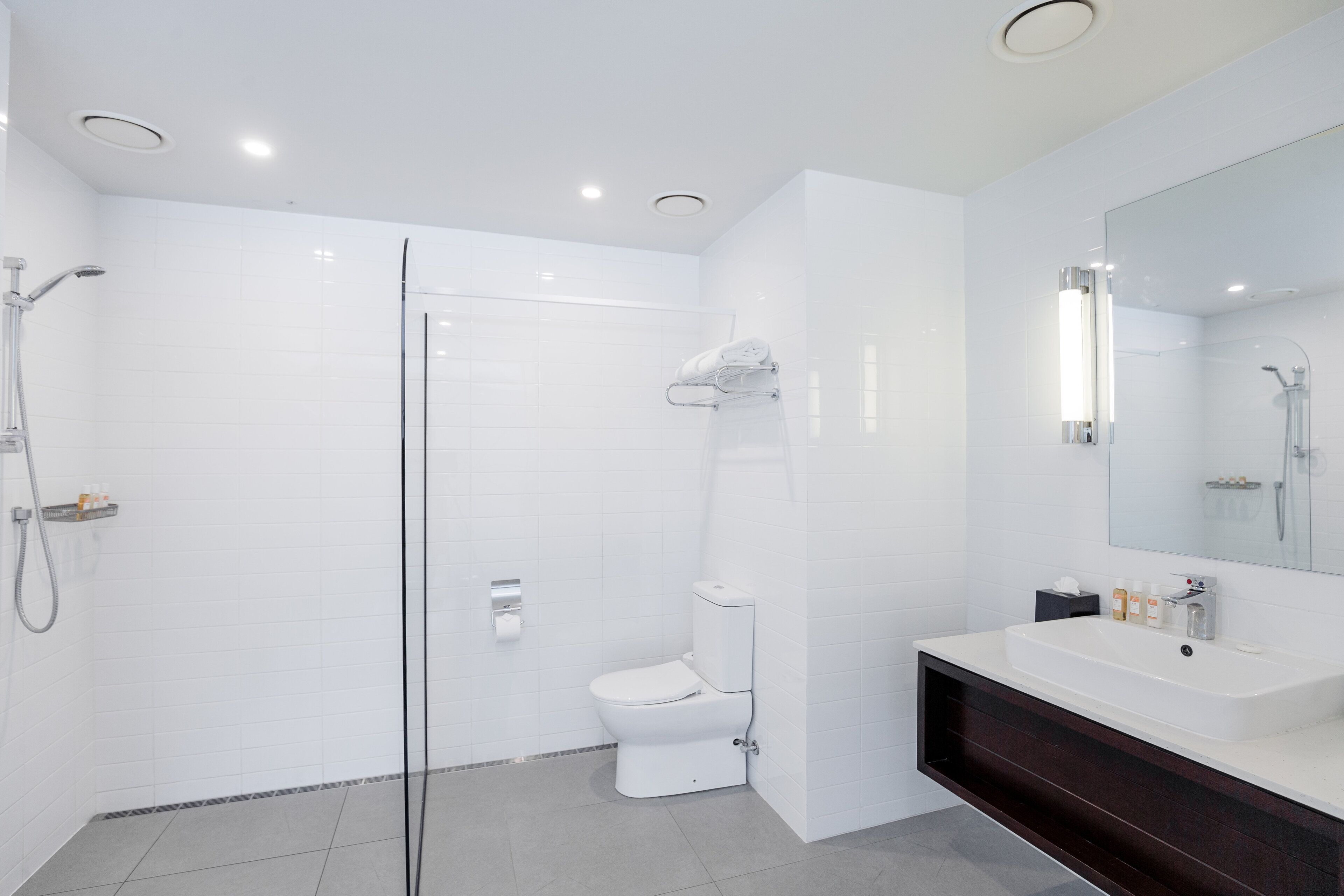 A modern bathroom with a glass-enclosed shower, a white toilet, and a vanity with a dark countertop.