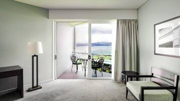 A hotel room with a balcony, a desk, a chair, and a sofa.