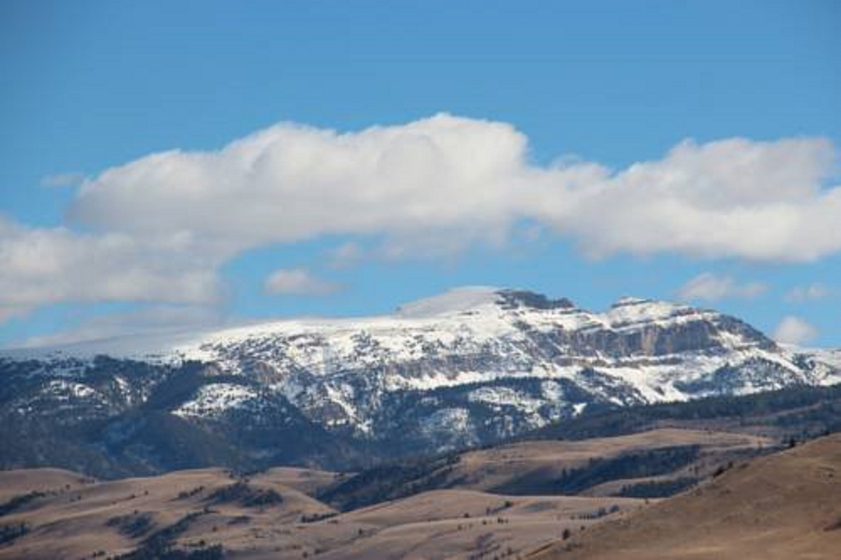 A mountain landscape with snow-capped peaks and a clear blue sky.
