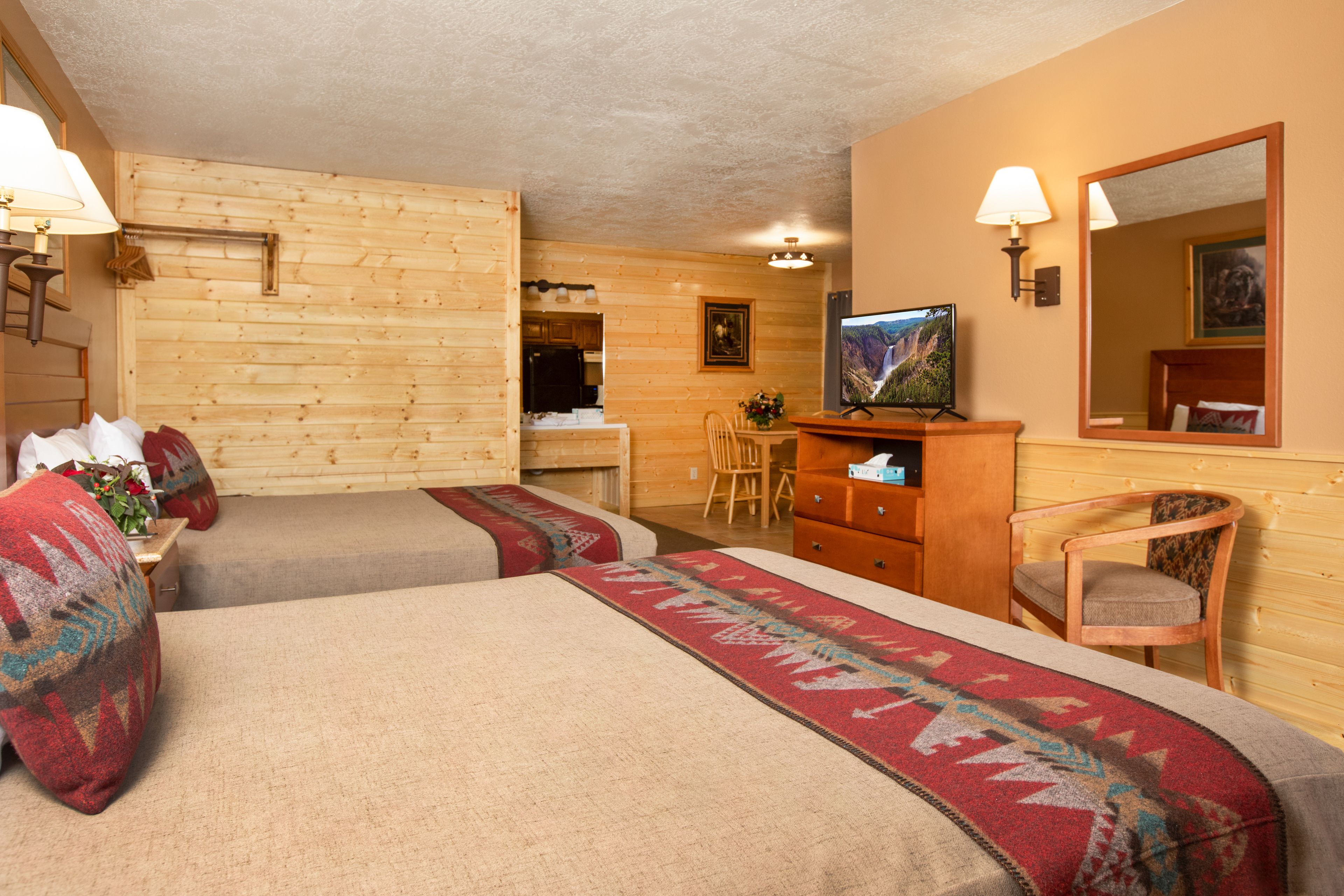 A cozy room with two beds, a television, a desk, and a chair.