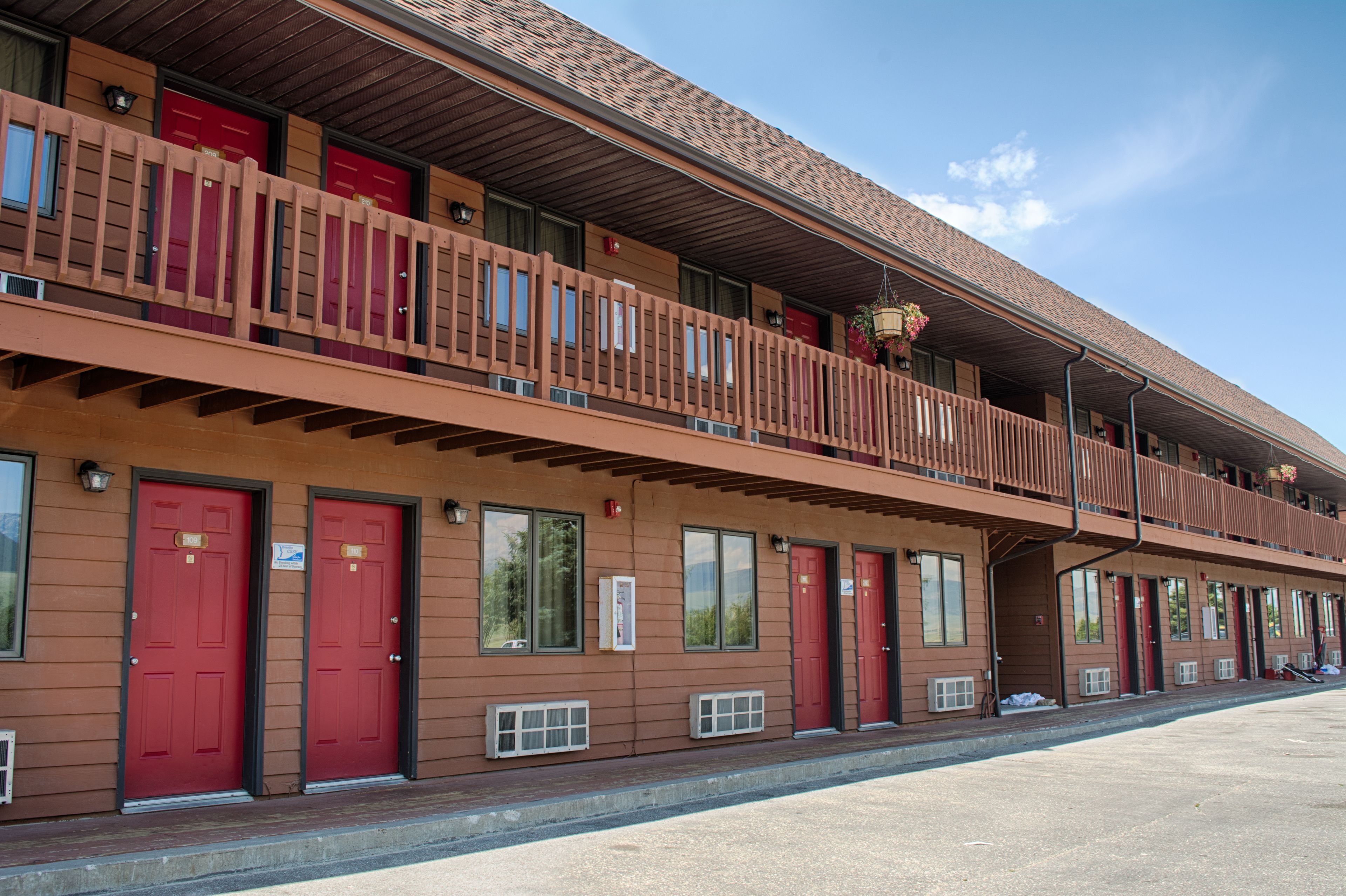 A motel with a two-story structure, featuring red doors and a balcony on the upper level.
