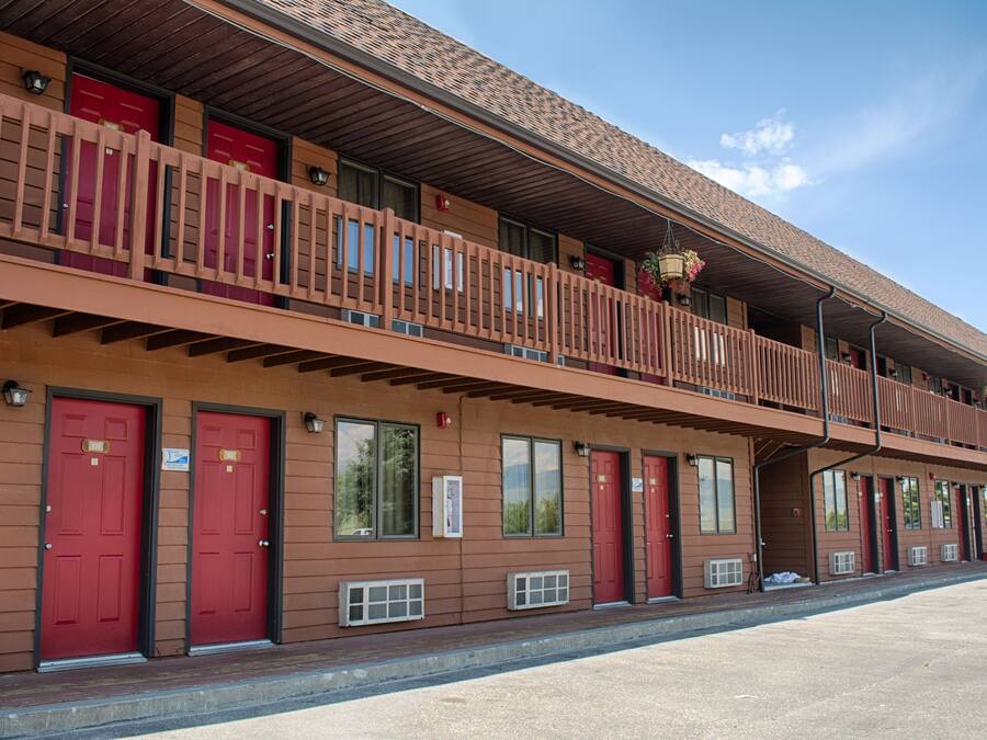 Ein Motel mit zweistöckiger Bauweise, mit roten Türen und einem Balkon im oberen Bereich.